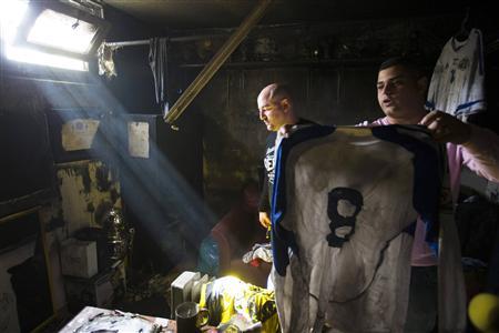 Employee of Beitar Jerusalem holds up a shirt that was damaged along with other items in a suspected arson attack in Jerusalem