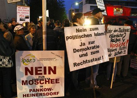 Demonstrators hold banners against the opening of the newly built Ahmadiyya mosque in the Heinersdorf district of Berlin