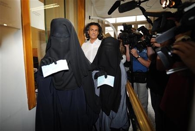 French businessman Rachid Nekkaz stands next to Halima and Imen after he paid their fines for wearing a niqab in Brussels